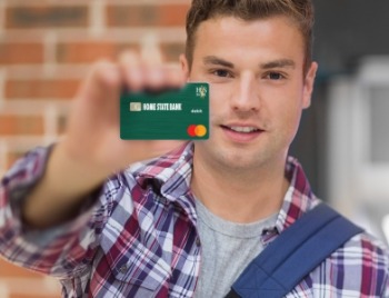 Student Checking and debit card.
young male student holding a Home State Bank Debit Card at a bank ATM machine.